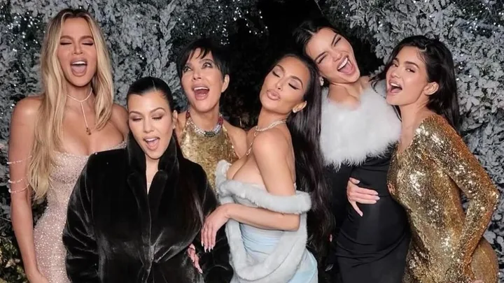 from left to right, Khloe Kardashian, Kourtney Kardashian, Kris Jenner, Kim Kardashian, Kendall Jenner and Kylie Jenner pose in gowns against a white christmas tree.