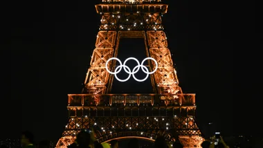Eiffel Tower at night with illuminated Olympic rings displayed in front.