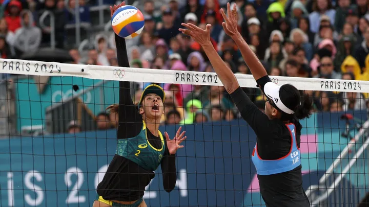 Female beach volleyball players scrap tiny uniform.