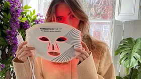 girl holds led light mask up to face