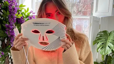 girl holds led light mask up to face