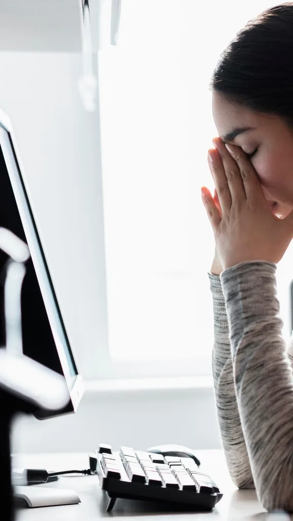 Woman with her head in her hands at her desk