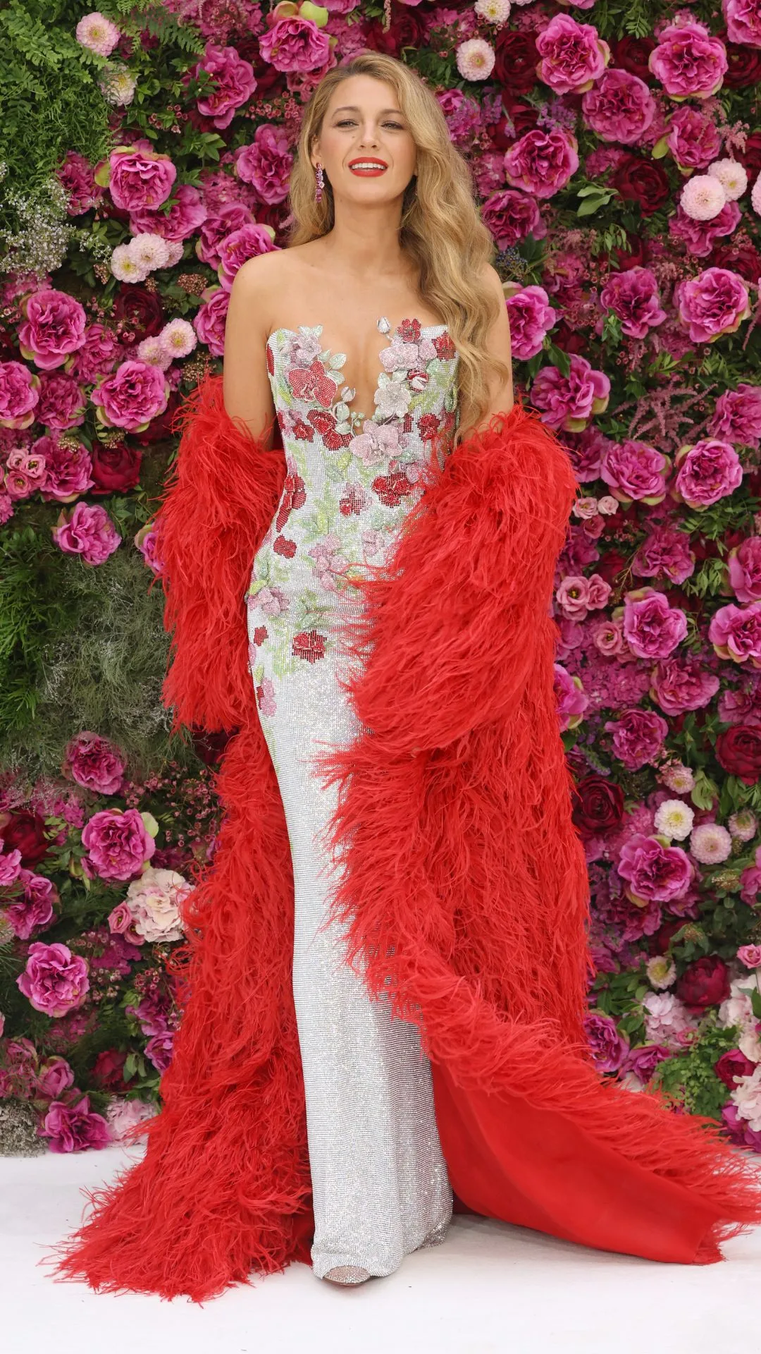 Blake Lively on the It Ends With Us red carpet wearing a floral column gown with a large feathered red cape.