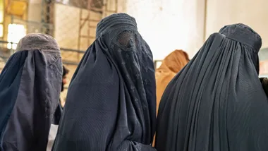 Afghan burqa-clad women stand in a queue as they wait to receive food aid from a non-governmental organisation (NGO) at a gymnasium in Kabul on January 17, 2023. - At least three leading international aid agencies have partially resumed life-saving work in Afghanistan, after assurances from the Taliban authorities that Afghan women can continue to work in the health sector. W