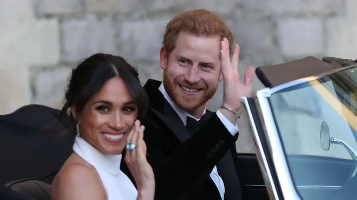 Duchess of Sussex and Prince Harry, Duke of Sussex wave as they leave Windsor Castle after their wedding to attend an evening reception at Frogmore House, hosted by the Prince of Wales on May 19, 2018 in Windsor, England.