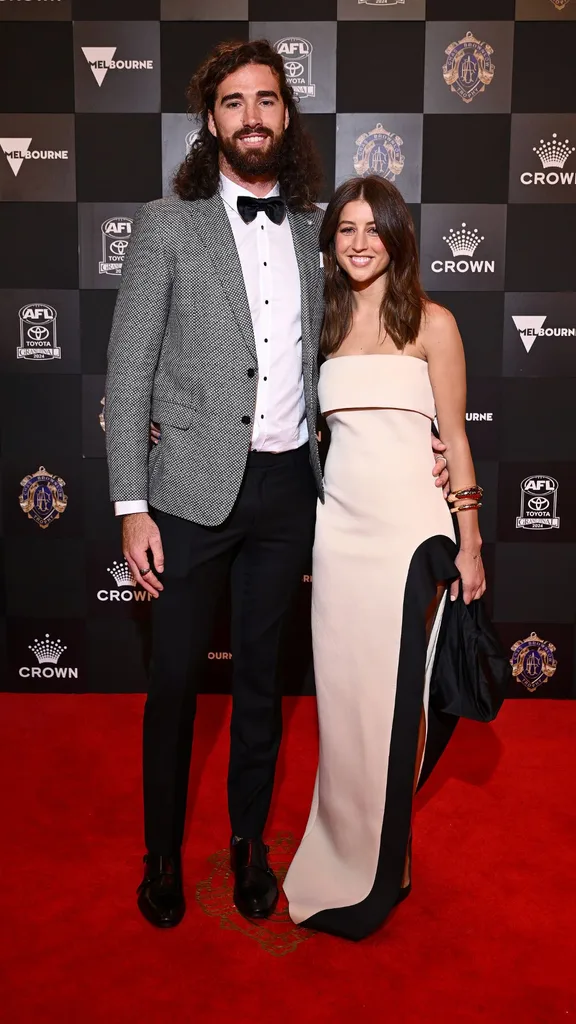 Alex Pearce of the Freemantle Dockers and partner Tara Bacovic in a white strapless gown with black slit detailing on the red carpet