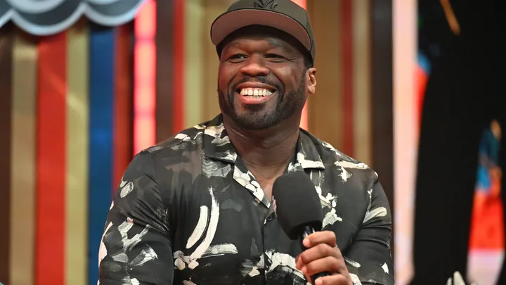 Curtis "50 Cent" Jackson speaks onstage during Day 3 of the 2024 Invest Fest at Georgia World Congress Center wearing a black baseball cap and a black and white graphic short sleeved shirt.