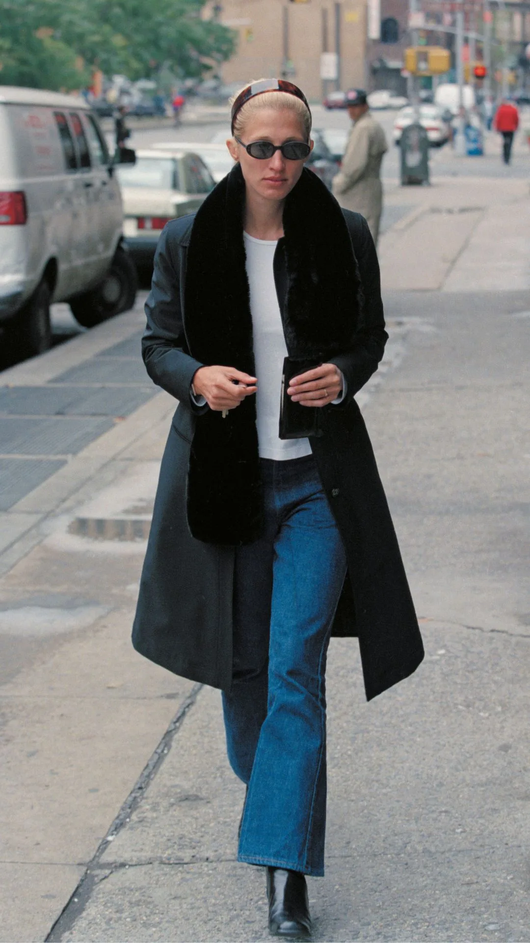 Carolyn Bessette walks in New York in a pair of blue jeans, white t-shirt and black fur-lined coat