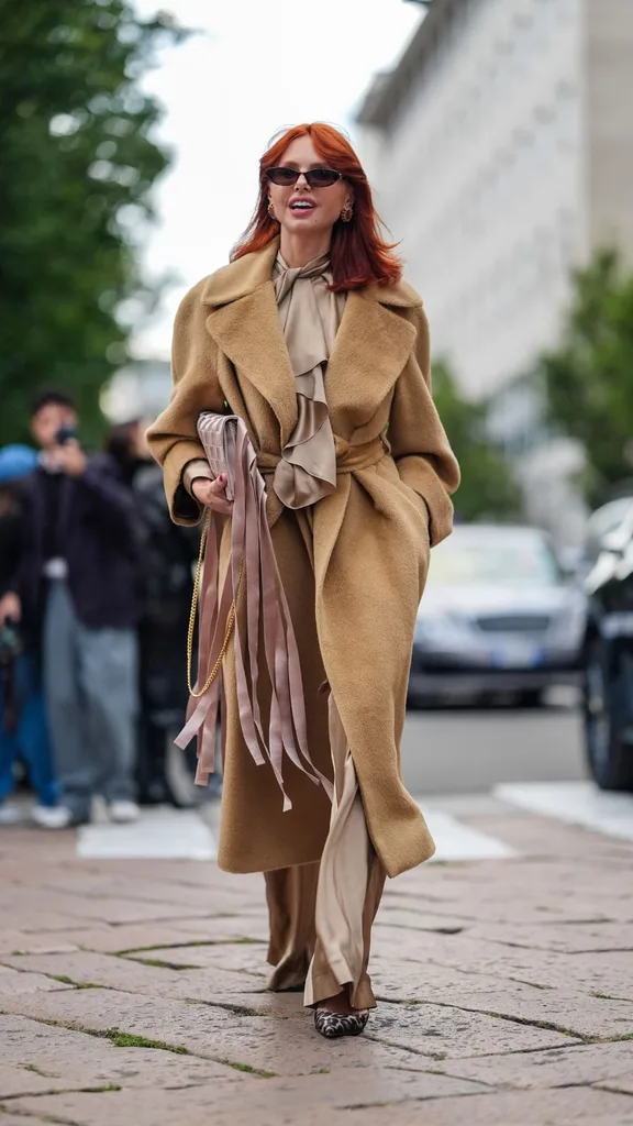 Red haired woman in black sunglasses, brown dress and coat at Milan Fashion Week