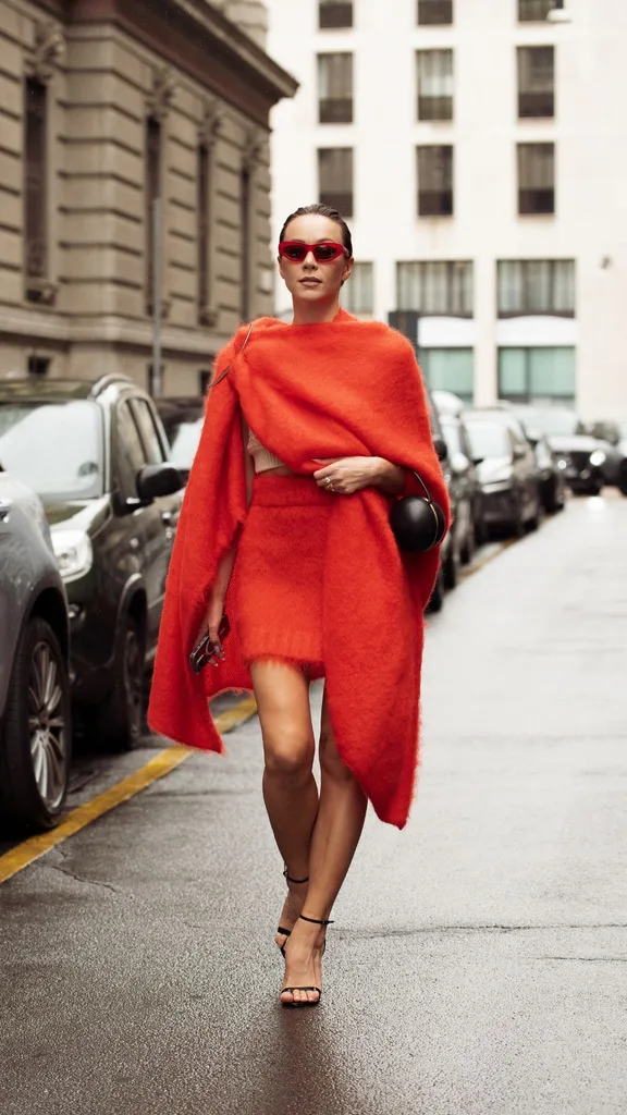 A woman wearing bright orange knitted skirt and top at Milan Fashion Week
