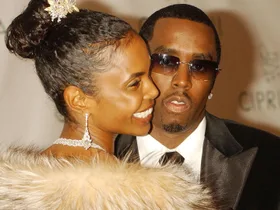 A close-up shot of Kim Porter looking over her shoulder wearing a feathered top with Sean 'Diddy' Combs looking into the camera wearing sunglasses