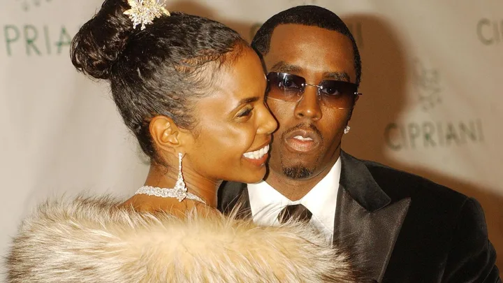 A close-up shot of Kim Porter looking over her shoulder wearing a feathered top with Sean 'Diddy' Combs looking into the camera wearing sunglasses