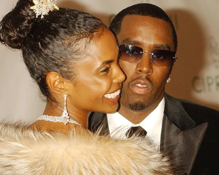 A close-up shot of Kim Porter looking over her shoulder wearing a feathered top with Sean 'Diddy' Combs looking into the camera wearing sunglasses