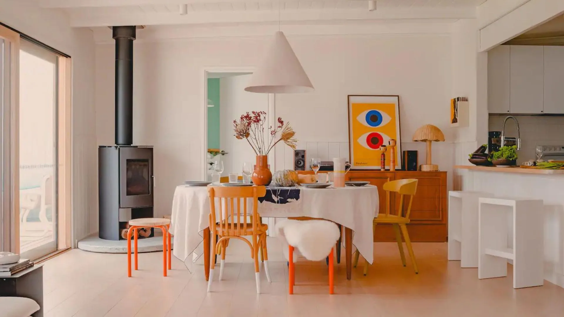 The colourful dining room at Phillip Island accommodation 'La Cabanon' a modern coastal airbnb with a mix of dining chairs.