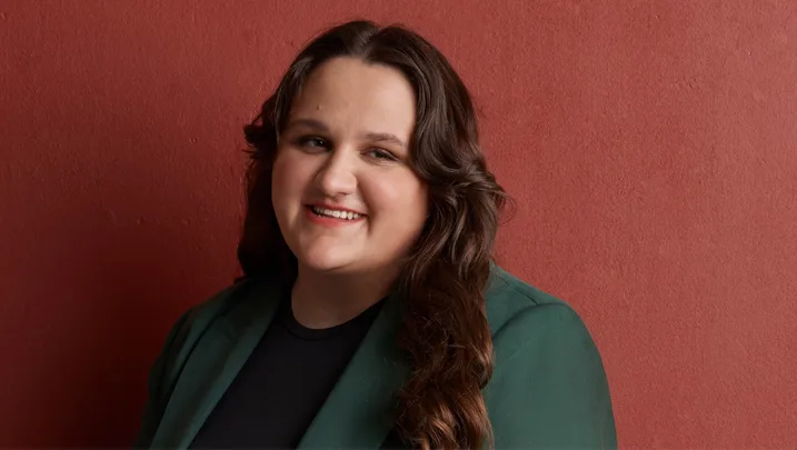 Sarah Williams CEO of What Were You Wearing Australia in a green suit against a dark red backdrop