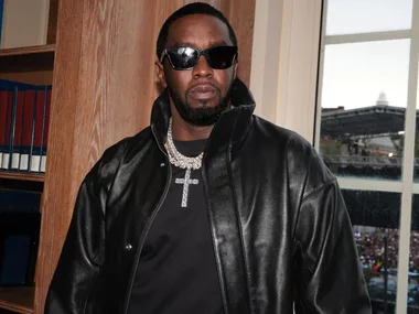 Sean "Diddy" Combs in a black leather jacket and black t shirt with large diamond necklace with a cross.