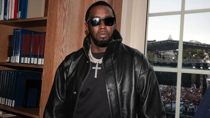 Sean "Diddy" Combs in a black leather jacket and black t shirt with large diamond necklace with a cross.