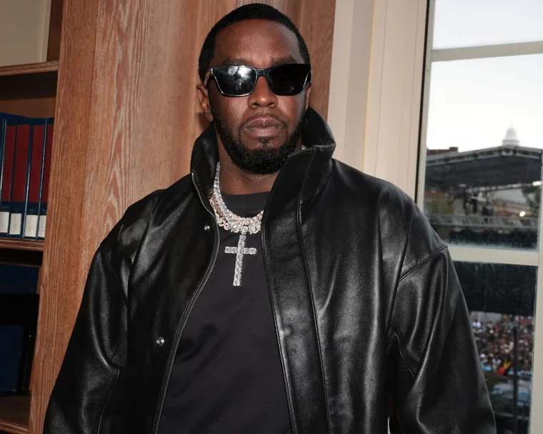 Sean "Diddy" Combs in a black leather jacket and black t shirt with large diamond necklace with a cross.