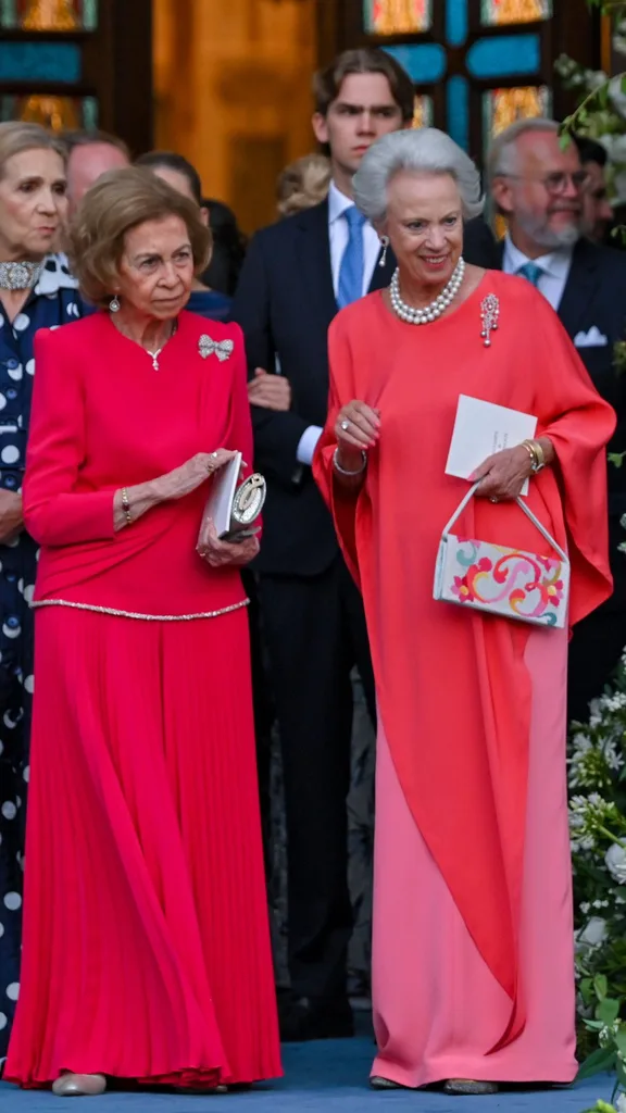 Queen Sofia and Princess Benedicta wearing bright salmon pink and red gowns with diamond broches.