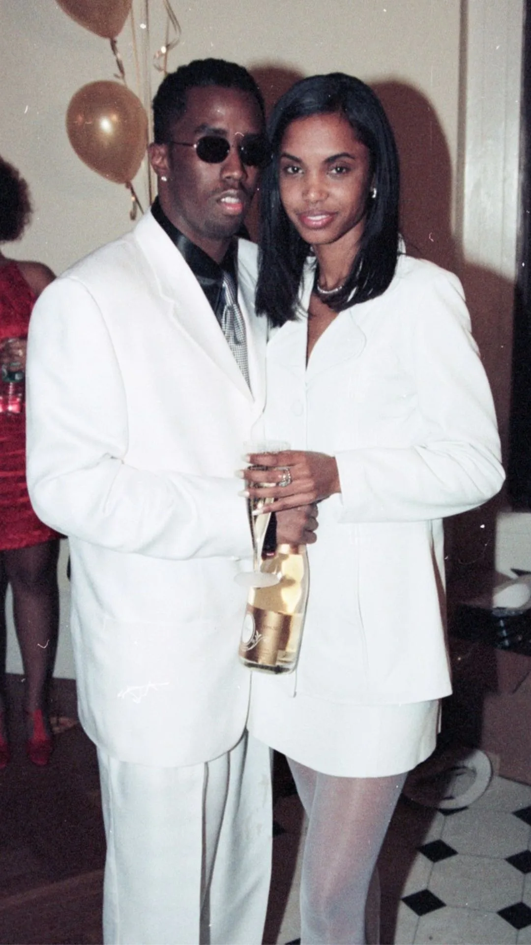 Portrait of American couple, rapper Sean Combs and Kimberly Porter (1970 - 2018), as they pose with a bottle of Louis Roederer Cristal Champagne during a New Year's Eve celebration, New York