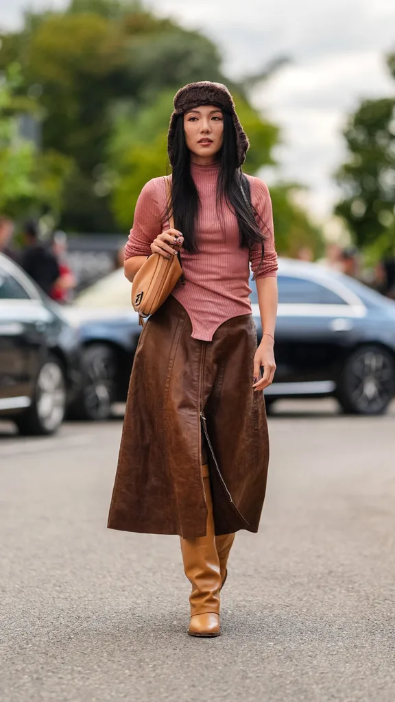 Yoyo Cao wearing brown leather skirt, tan biker boots and pink long sleeve top at Milan Fashion Week
