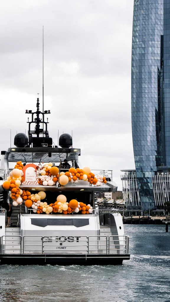 Superyacht sailing around sydney harbour styled with abundant orange balloons.