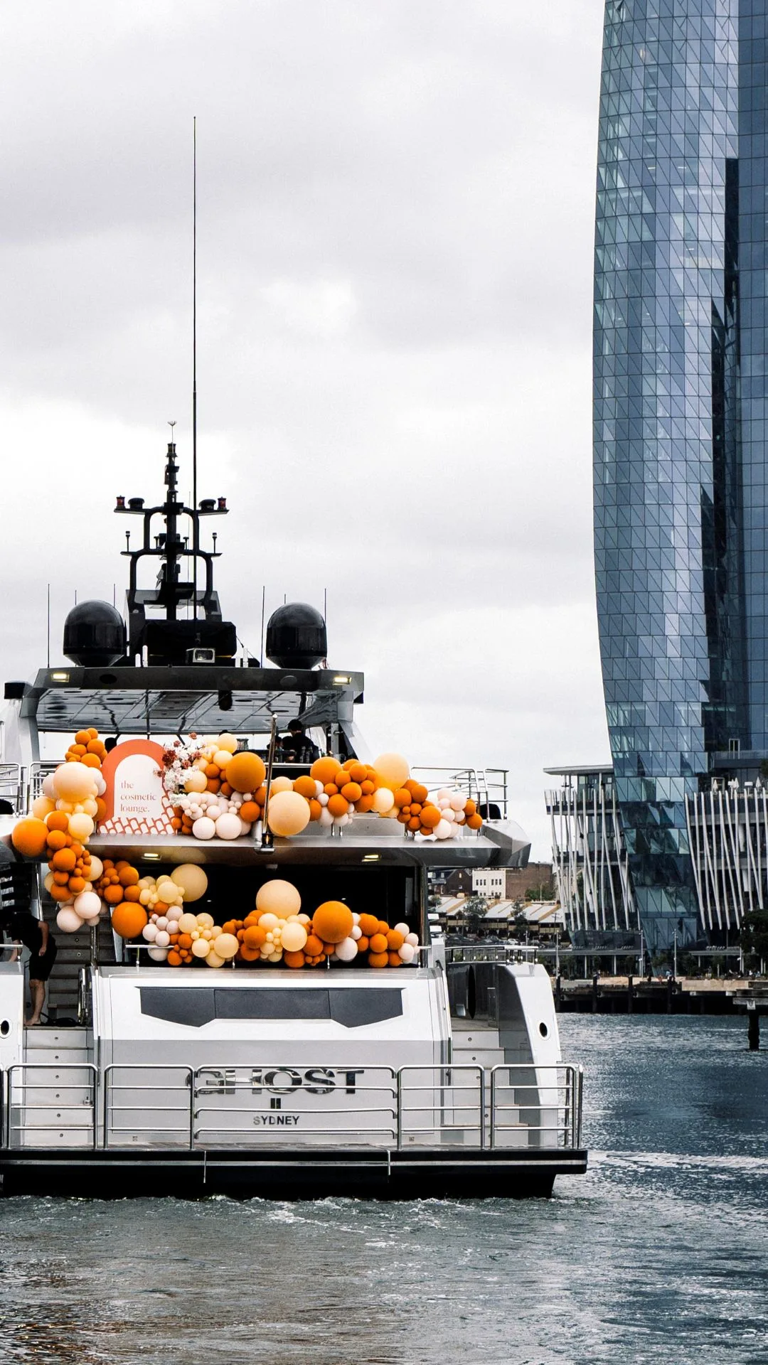 Superyacht sailing around sydney harbour styled with abundant orange balloons. 