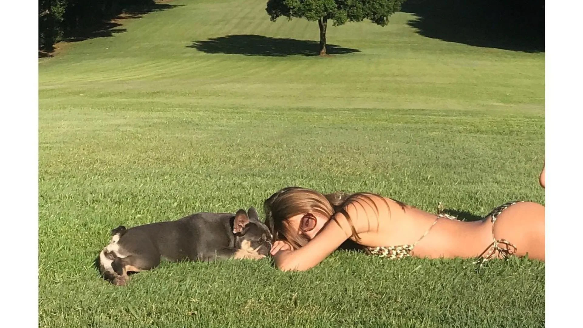 An instagram post from Liam Hemsworth's girlfriend Gabriella Brooks shown lying on the grass in a bikini with his dog. 