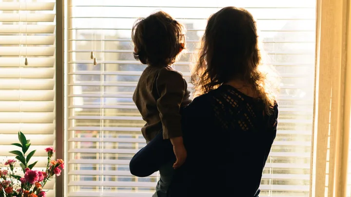 rear view of mother and baby standing against window