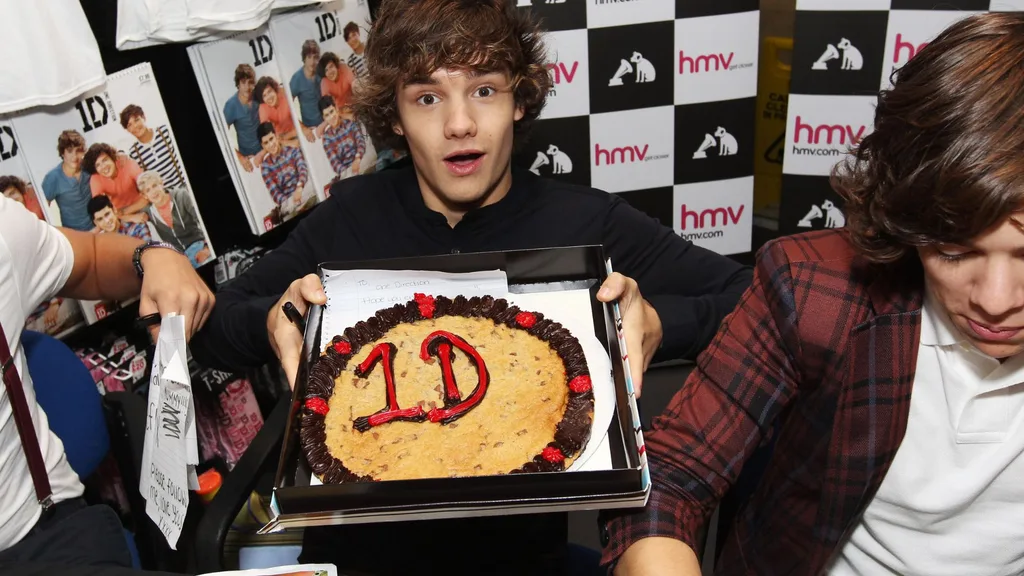 Liam Payne of One Direction shows a cake while visiting Glasgow, Manchester and London on September 11, 2011. The tour was taken in a luxury helicopter to launch their first single 'What Makes You Beautiful'