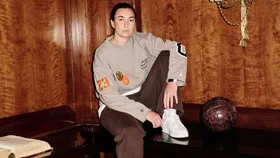 Goalkeeper for the Matildas, Mackenzie Arnold poses for a portrait in a wooden panelled room sitting on a mahogany bench a beige and brown tracksuit ahead of The Best FIFA Football Awards 2023