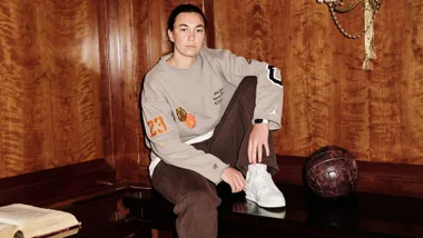 Goalkeeper for the Matildas, Mackenzie Arnold poses for a portrait in a wooden panelled room sitting on a mahogany bench a beige and brown tracksuit ahead of The Best FIFA Football Awards 2023