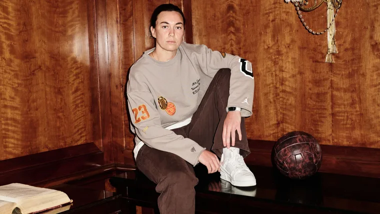 Goalkeeper for the Matildas, Mackenzie Arnold poses for a portrait in a wooden panelled room sitting on a mahogany bench a beige and brown tracksuit ahead of The Best FIFA Football Awards 2023