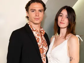 Monsters star Nicholas Alexander Chavez in a black suit poses with girlfriend Victoria Abbott who is wearing a white spaghetti strap dress.