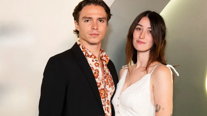 Monsters star Nicholas Alexander Chavez in a black suit poses with girlfriend Victoria Abbott who is wearing a white spaghetti strap dress.