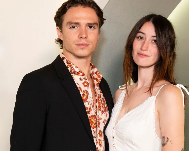 Monsters star Nicholas Alexander Chavez in a black suit poses with girlfriend Victoria Abbott who is wearing a white spaghetti strap dress.