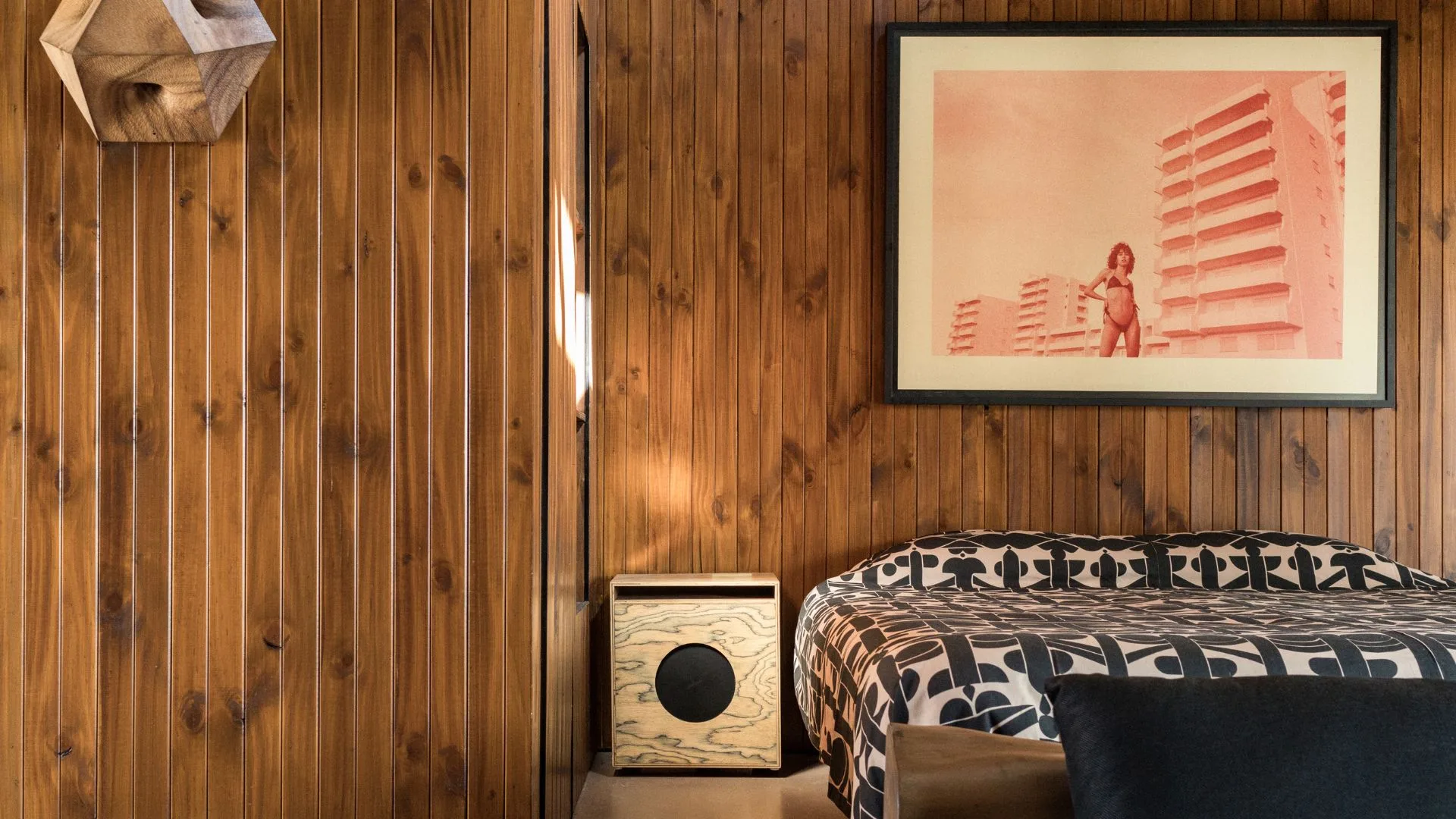 A bedroom at Sea Sea Hotel with retro wooden vj panelling on the walls and ceiling, and a surf print artwork on the back wall. 