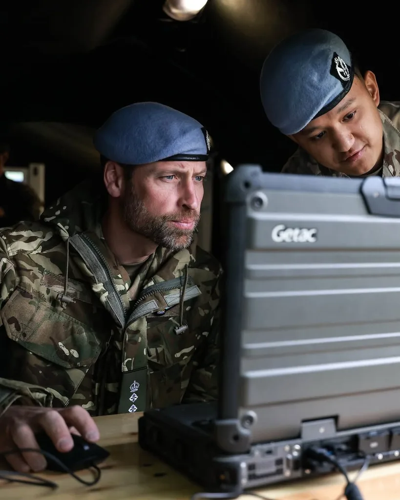 Two men dressed in military gear reading a computer screen