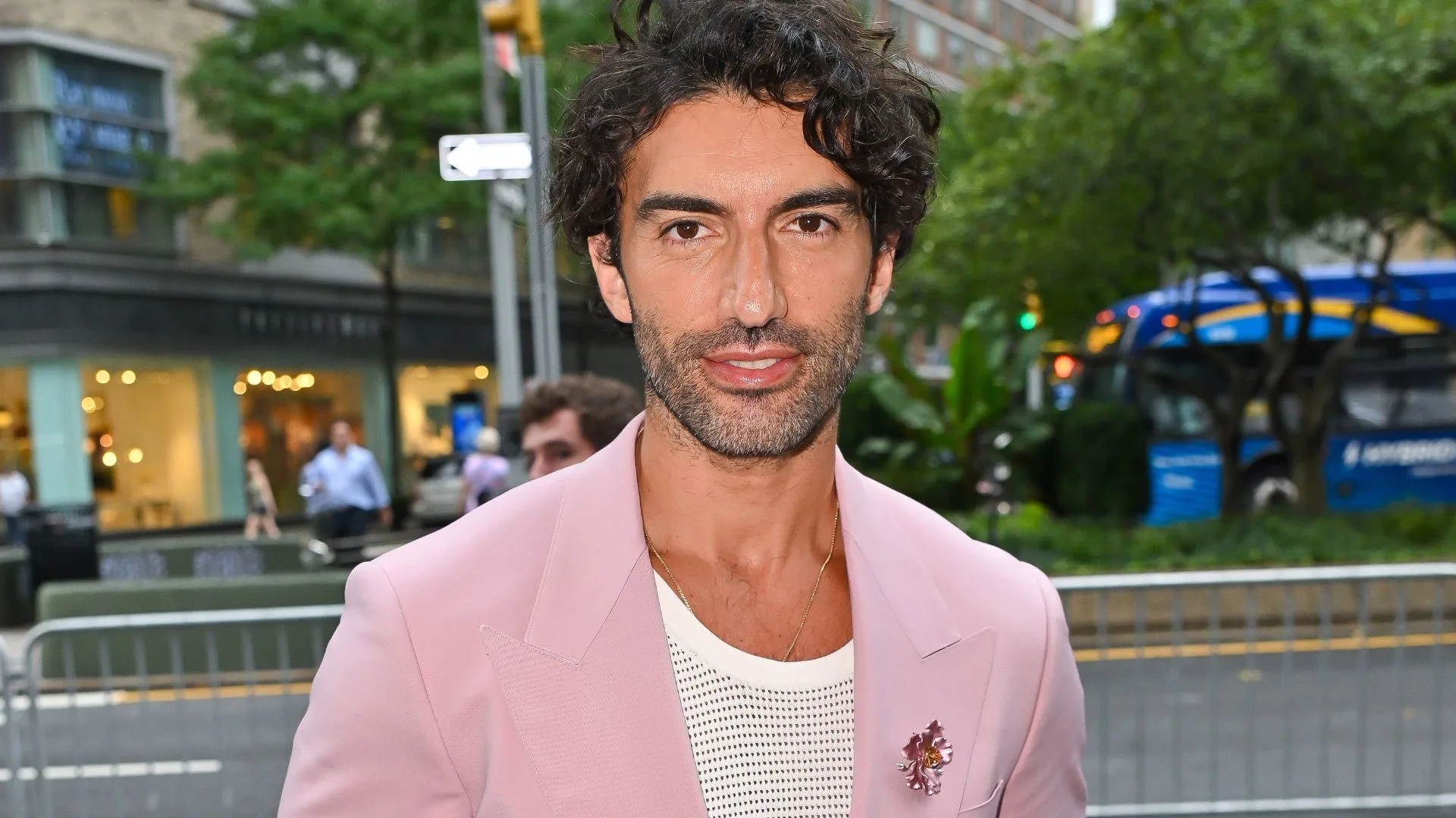 A man wearing a pink suit and white t shirt smiling. 