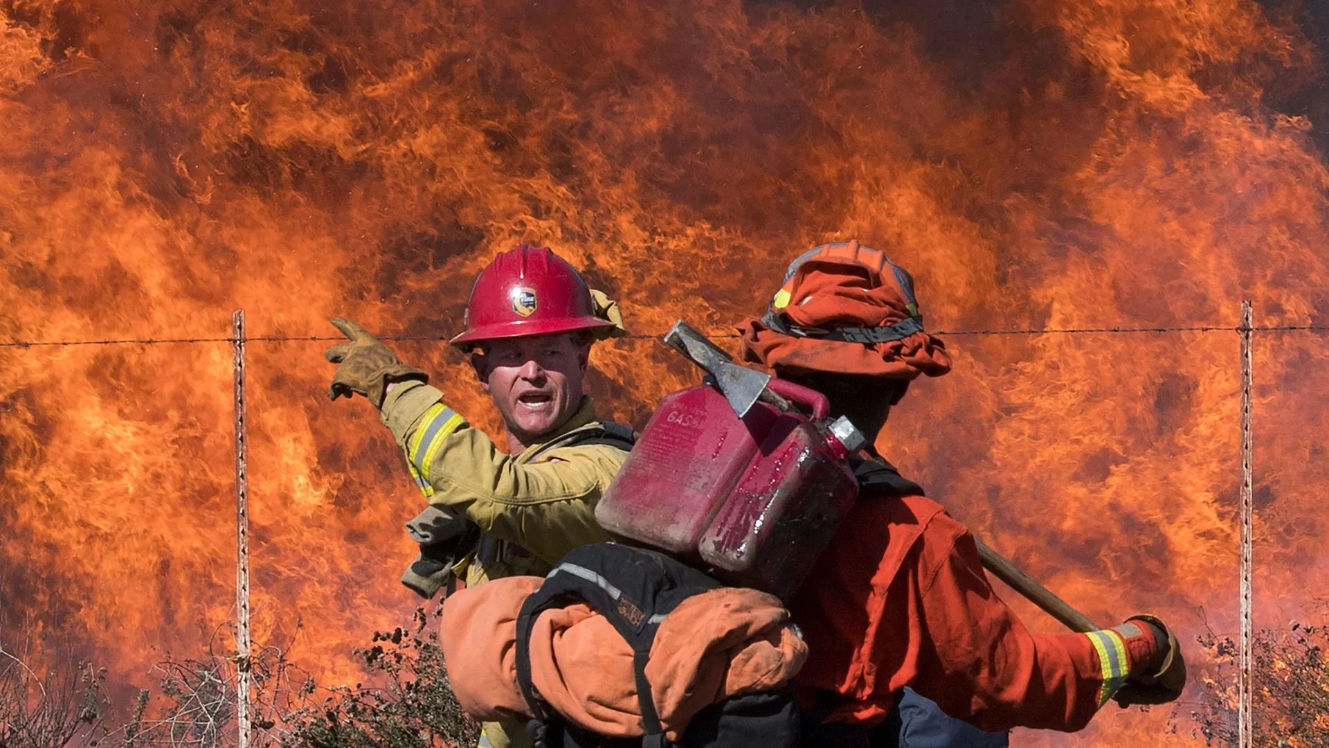 A firefighter (L) speaks to an inmate firefighter as they prepare to put out flames on the road leading to the Reagan Library during the Easy Fire in Simi Valley, California on October 30, 2019.