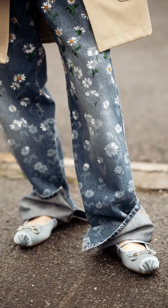 Photo os jeans with flowers on them and blue ballet flats.