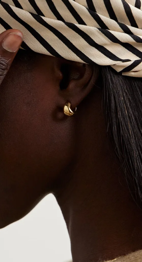 Person wearing chunky huggie earrings