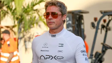 A man wearing a tight fitting white jumpsuit and orange sunglasses.