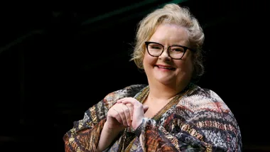 A woman wearing glasses smiling.