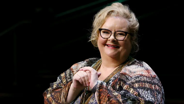 A woman wearing glasses smiling.