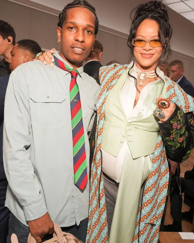 A man and woman stand arm in arm smiling at the Dior mens fashion show