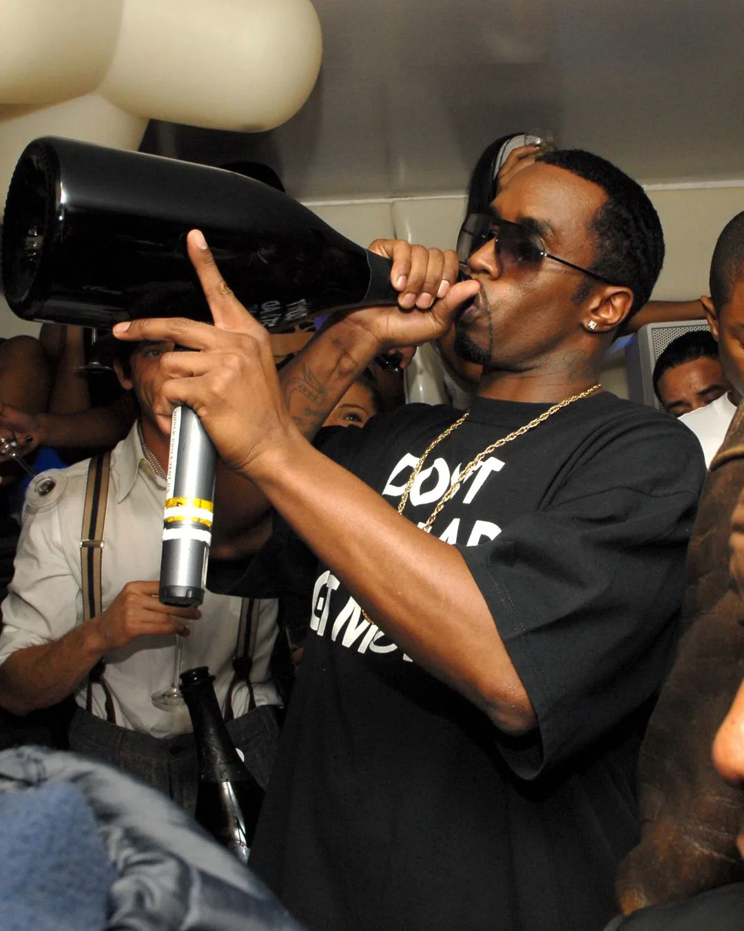 Sean Diddy Combs drinking from a large Champagne bottle. 