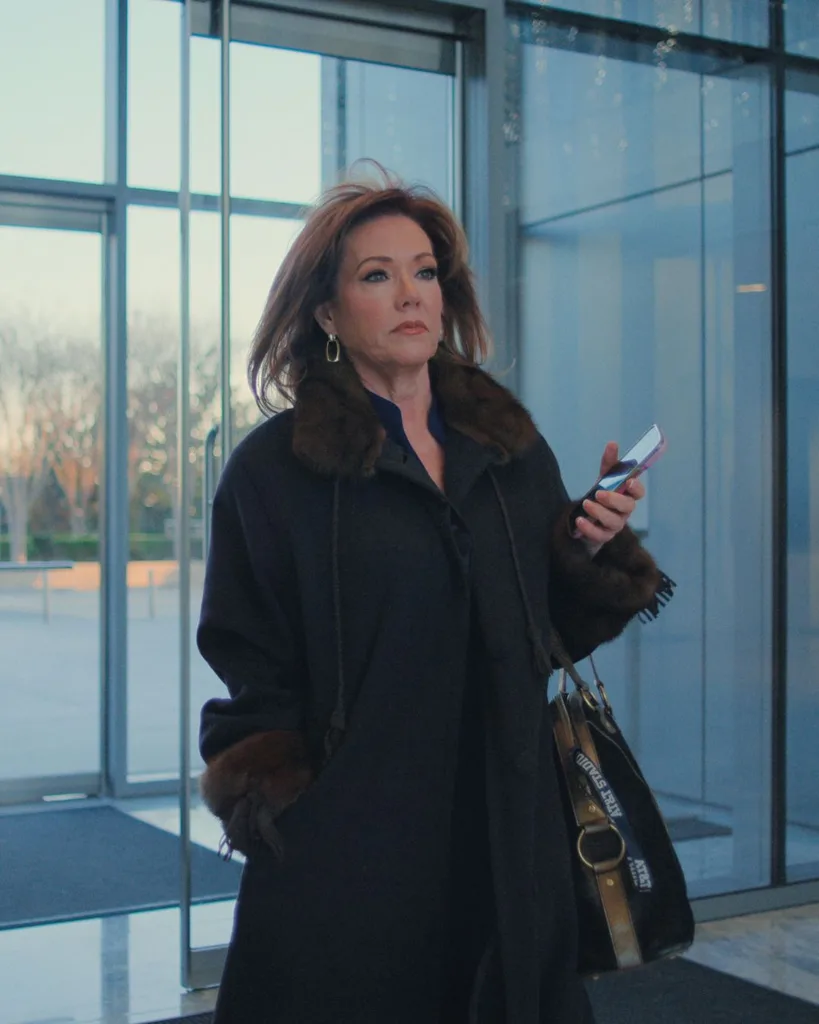 A woman wearing a fur lined coat walking into the lobby of a building.