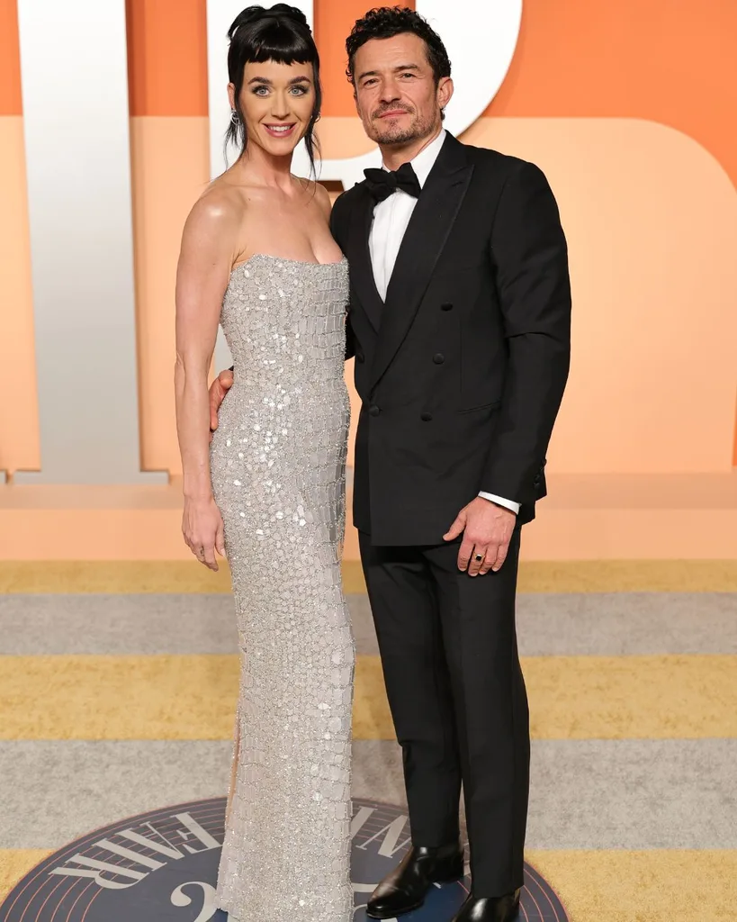 katy perry in a silver dress with orlando bloom on a red carpet