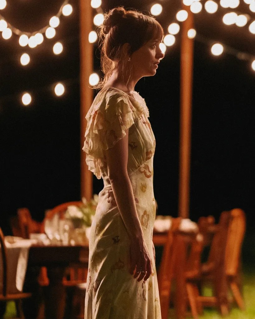A woman standing in backyard at night a yellow dress.
